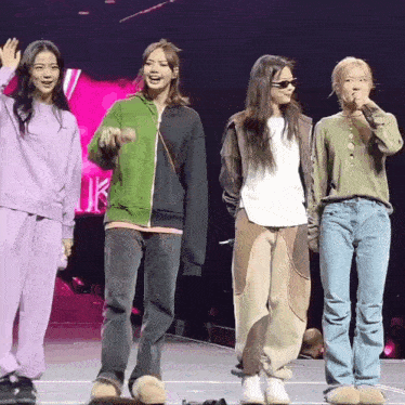a group of women are standing on a stage and one of them is wearing a green jacket