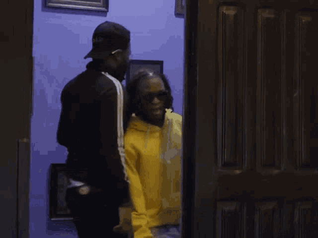 a man in a yellow hoodie is standing next to a man in a black jacket