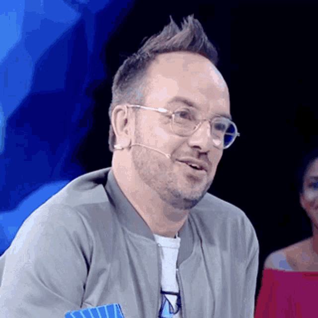 a man wearing glasses and a jacket with a microphone in his ear