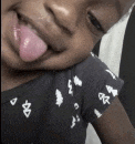 a little girl sticking her tongue out while wearing a black shirt