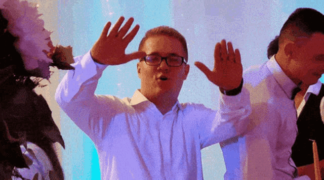 a man wearing glasses is making a funny face with his hands in the air