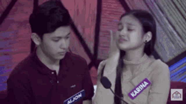 a boy and a girl are sitting next to each other . the girl has a name tag that says karina on it .