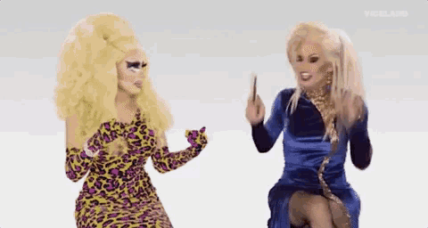 two drag queens are sitting next to each other and talking . one of the drag queens is wearing a leopard print dress .