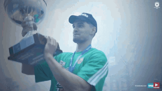 a man in a green shirt is holding a trophy in his hands
