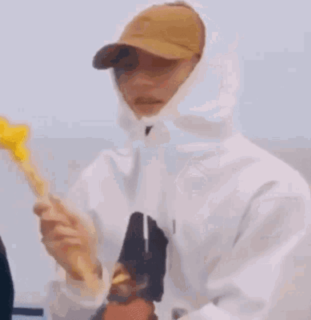 a man wearing a hoodie and a hat is holding a yellow object .
