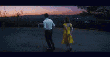 a man in a white shirt and a woman in a yellow dress are standing next to each other on a road .