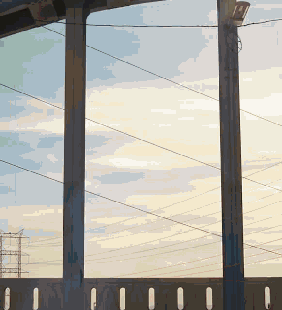 a bridge with a lot of power lines and a sunset in the background