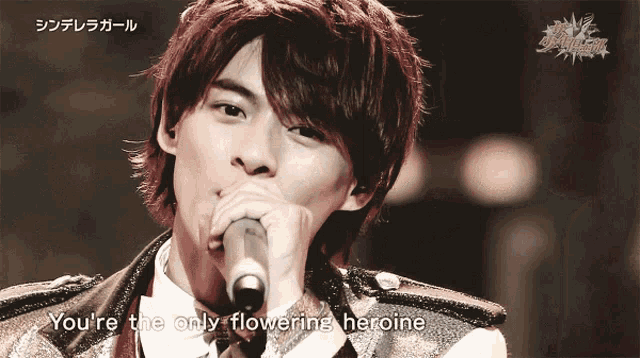 a young man singing into a microphone with the words " you 're the only flowering heroine " below him