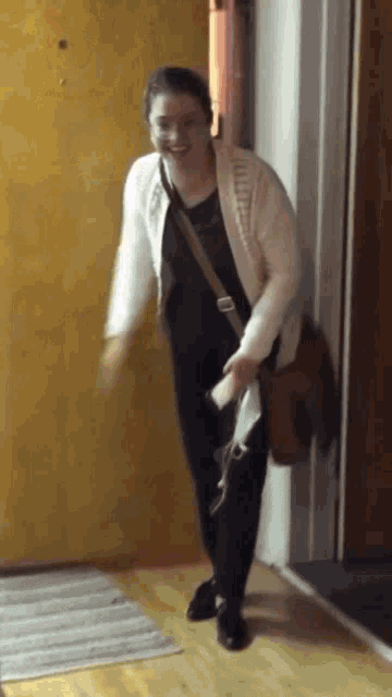 a woman standing in front of a yellow door with a brown bag on her shoulder