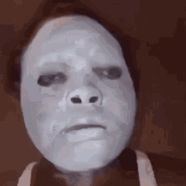 a close up of a person wearing a white mask on their face