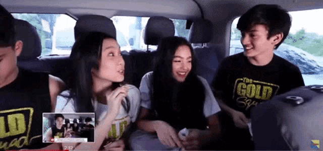 a group of people are sitting in a car and one of them is wearing a shirt that says the gold squad