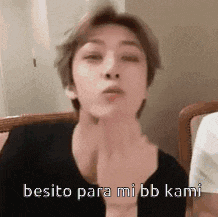 a man is blowing a kiss while sitting in a chair with the words besito para mi bb kami .