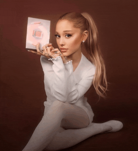a woman with a ponytail is holding a box with a g on it