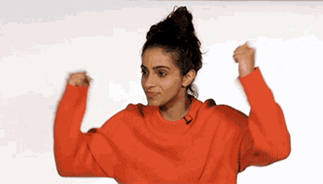 a woman in a red sweater is flexing her muscles against a white background .
