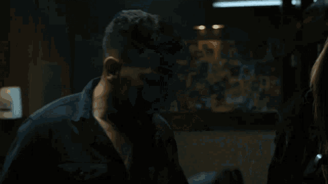 a woman in a leather jacket is standing in a dark room