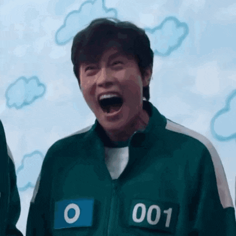 a man in a squid game uniform is laughing with his mouth wide open .