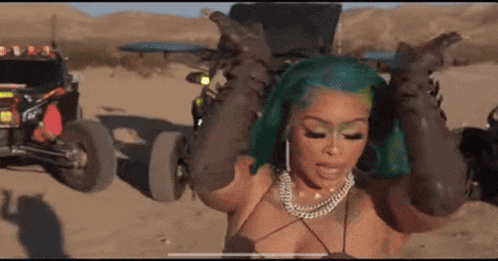 a woman with green hair is standing in the desert in front of a row of atv 's .