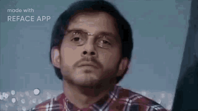 a man wearing glasses and a plaid shirt is making a face .