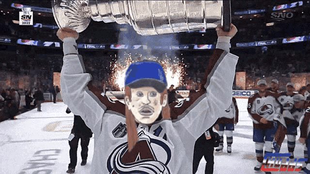 a hockey player holds up a trophy in front of a sign that says sno on it