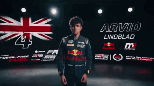 a man in a red bull jacket stands in front of a british flag