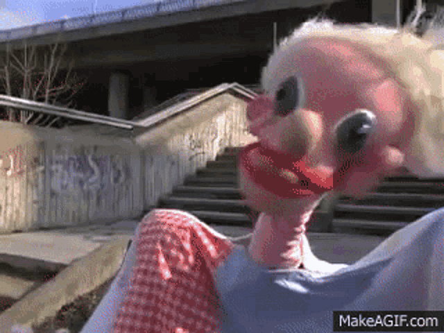 a clown puppet is sitting on the ground in front of a set of stairs