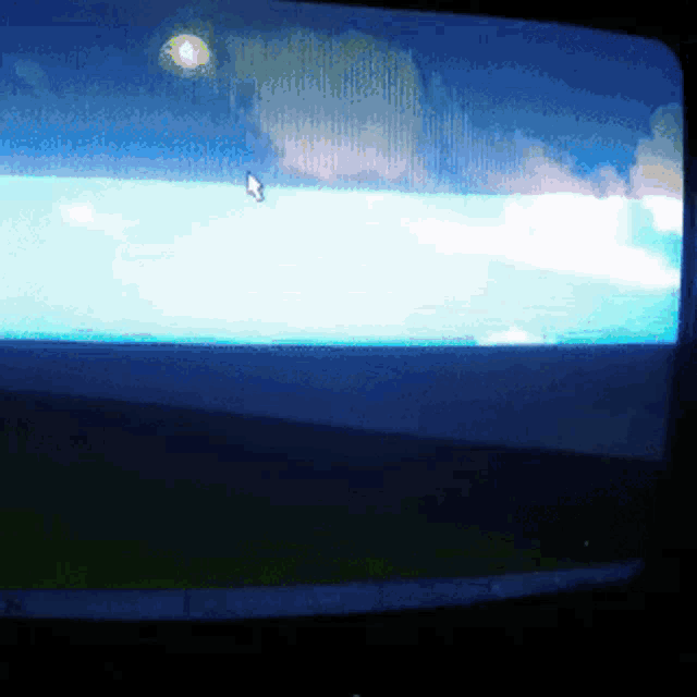 a computer monitor shows a blue sky with clouds and a mouse pointer
