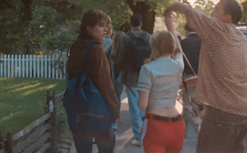 a group of people walking down a street with a man holding a woman 's back
