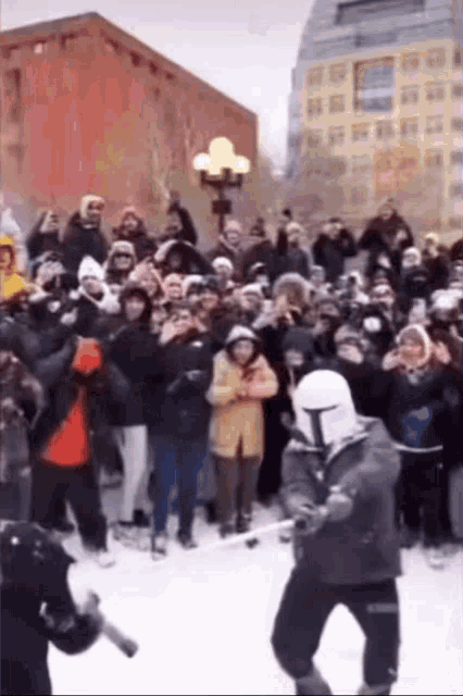 a man in a storm trooper costume is holding a lightsaber in front of a crowd of people .