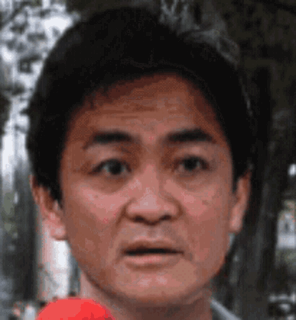 a close up of a man 's face with a red object in his mouth
