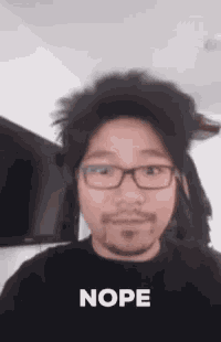 a man with glasses and a beard is making a funny face and says nope .