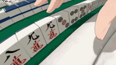 a person is playing mahjong with chinese characters on the blocks