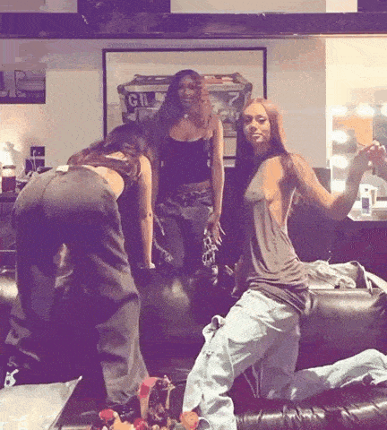a group of women are posing for a picture in a room with a sign that says gil on it .