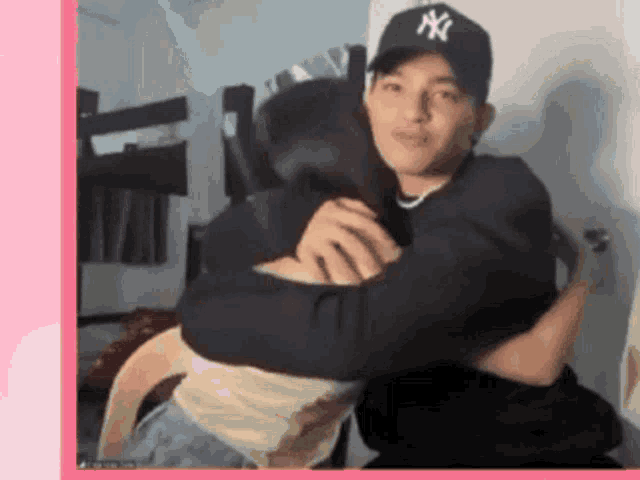 a man wearing a ny hat is hugging a girl