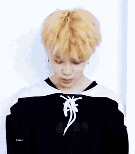 a young man with blonde hair is wearing a black and white shirt with a lace up neckline