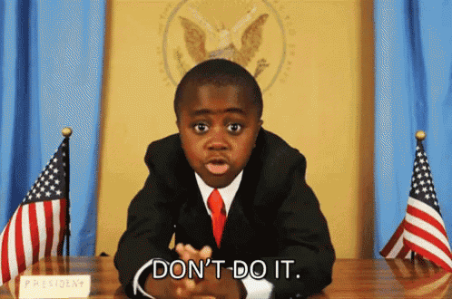 a young boy in a suit and tie is sitting at a desk with a sign that says president on it