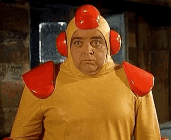 a man in a yellow and red costume with a red helmet on his head and shoulder pads .