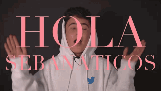 a young man wearing a white hoodie is standing in front of a sign that says hola sebanauticos