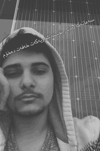 a man wearing a hooded sweater with arabic writing on his face