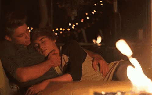 two boys are laying on a couch with a candle in the background