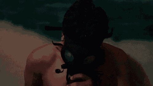 a man without a shirt is wearing a gas mask .
