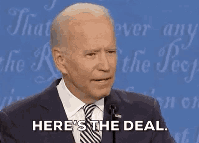 a man in a suit and tie is standing in front of a microphone and says here 's the deal .