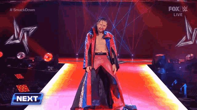 a man in a red and black robe stands on a stage with a fox live logo in the background