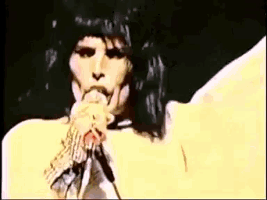 a close up of a person singing into a microphone with their mouth open