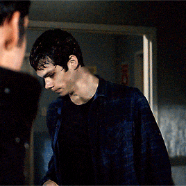 a young man in a blue plaid shirt is looking at another man