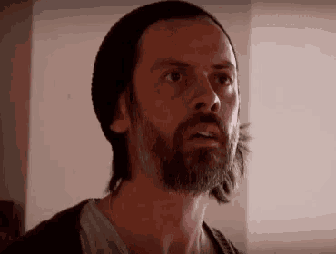 a man with a beard is wearing a beanie and looking up