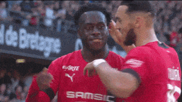 a soccer player wearing a red shirt that says samsic