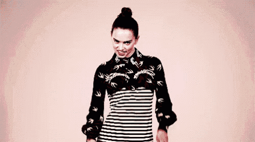 a woman in a striped dress is giving a peace sign with her hands .