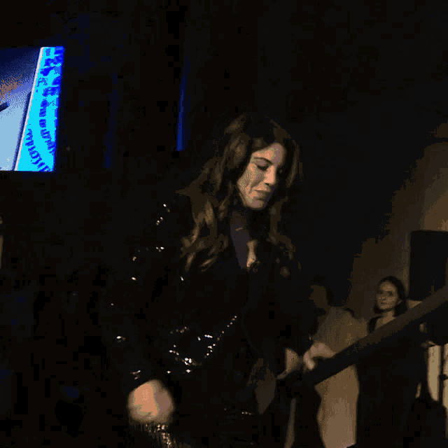 a woman in a black sequined jacket is smiling and dancing
