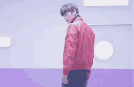 a man in a red jacket stands in a purple room