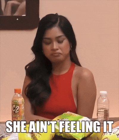a woman sitting at a table with a bag of chips and the words she ain t feeling it